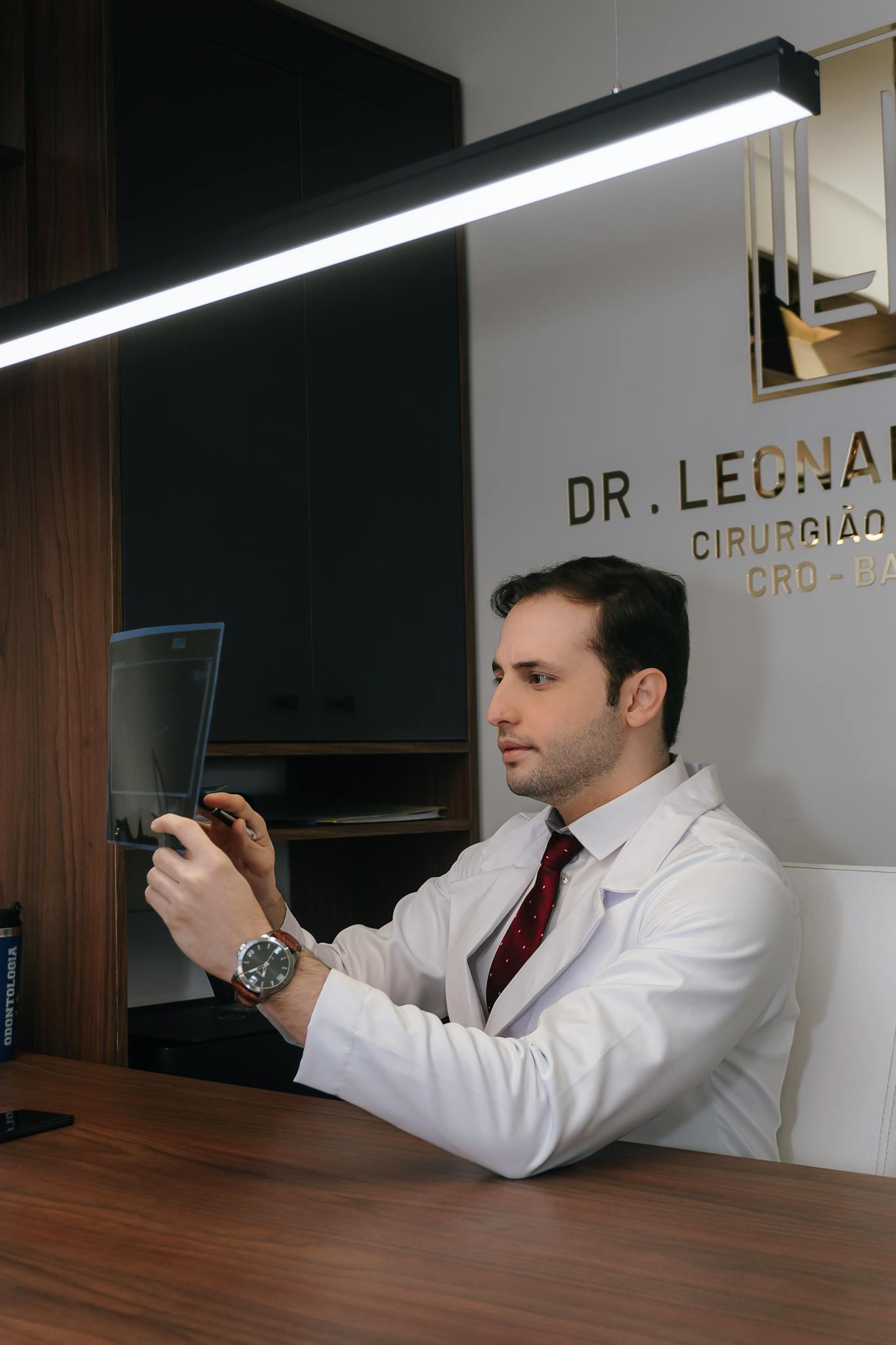 Medical professional examining radiographic image in clinical office setting.